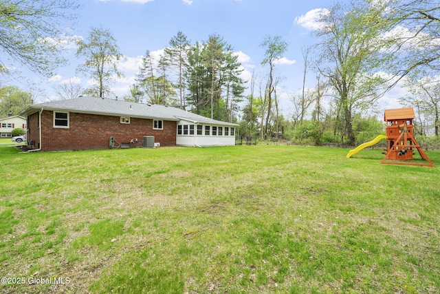 view of grassy yard with a playground and cooling unit