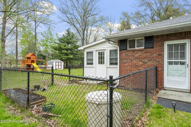 view of side of home featuring a shed, brick siding, a shingled roof, an outdoor structure, and a gate