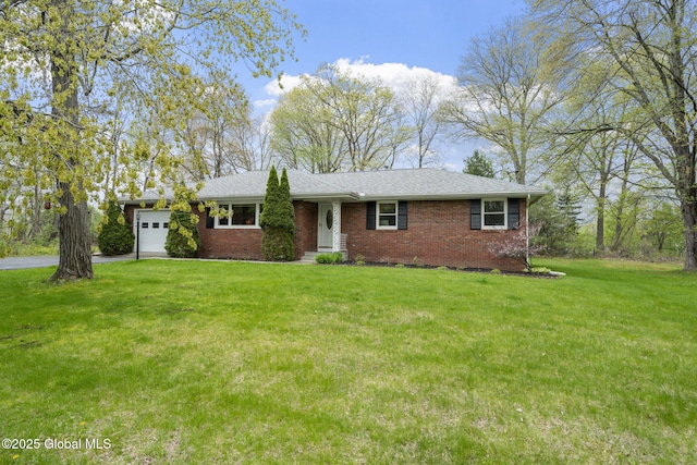 ranch-style house with an attached garage, driveway, a front yard, brick siding, and a shingled roof