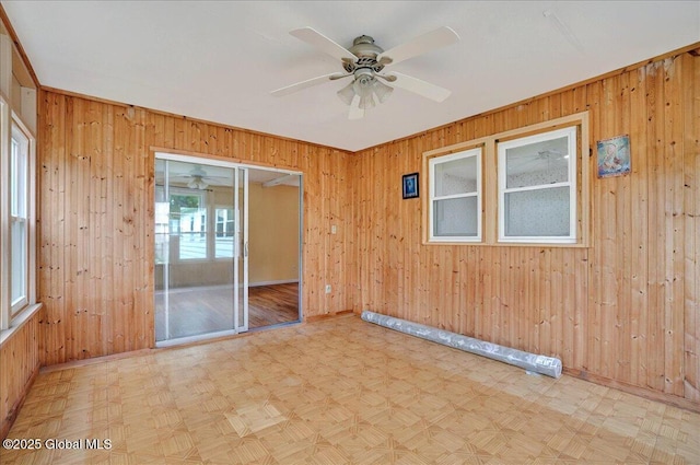 spare room featuring wooden walls, tile patterned floors, ceiling fan, and baseboards