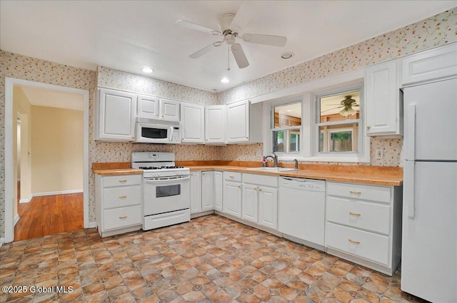 kitchen with white appliances, a sink, light countertops, white cabinetry, and ceiling fan