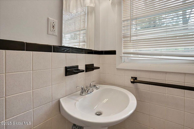 bathroom featuring a sink and tile walls