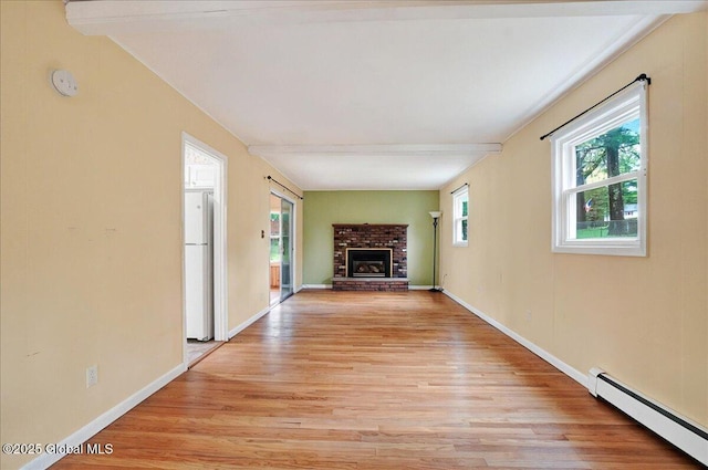 unfurnished living room featuring a baseboard heating unit, light wood-style floors, beamed ceiling, a fireplace, and baseboards