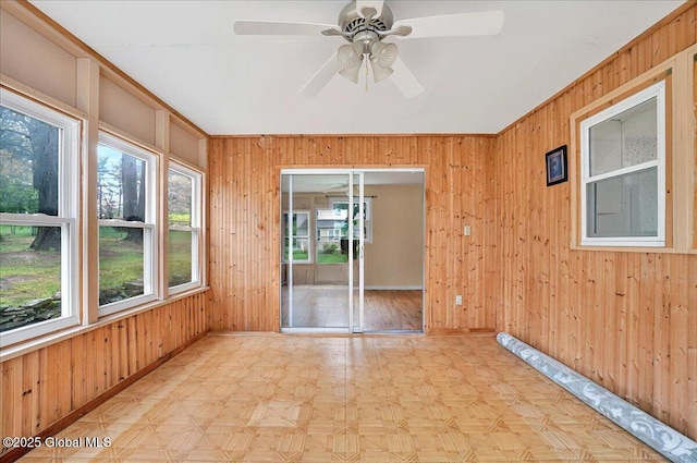 spare room featuring wood walls, ceiling fan, and baseboards