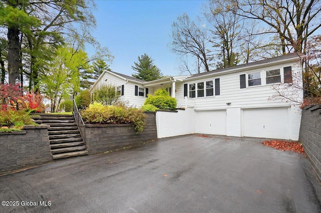 ranch-style house featuring stairs, asphalt driveway, and an attached garage