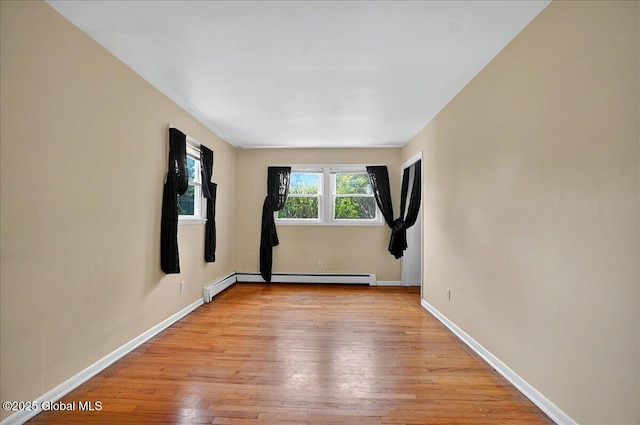 unfurnished room with light wood-style flooring, a baseboard radiator, and baseboards