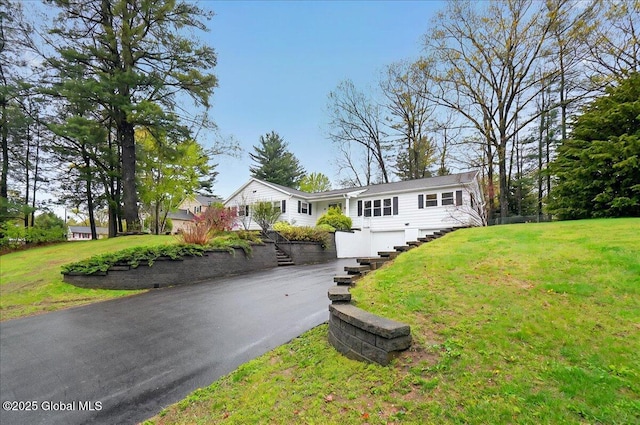 ranch-style home featuring a garage, stairway, asphalt driveway, and a front yard