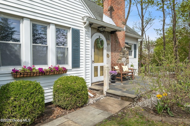 property entrance with roof with shingles and a chimney