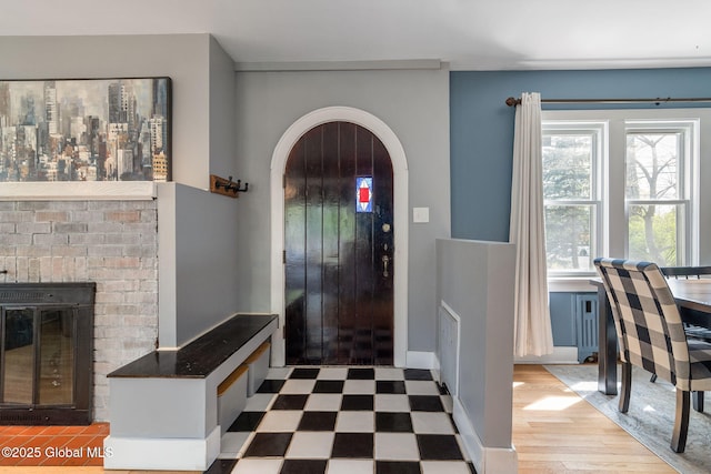 entryway with arched walkways, a brick fireplace, and tile patterned floors
