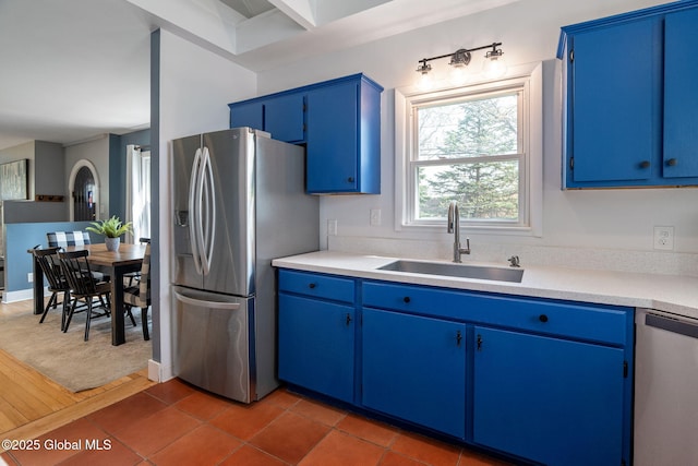 kitchen featuring light countertops, a sink, appliances with stainless steel finishes, and blue cabinetry