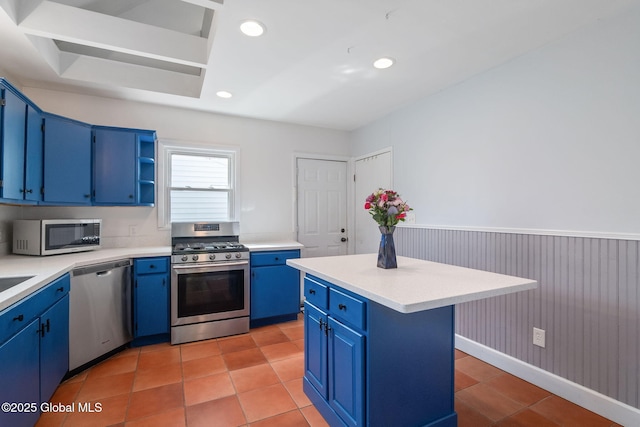 kitchen with light countertops, appliances with stainless steel finishes, a kitchen island, and blue cabinetry