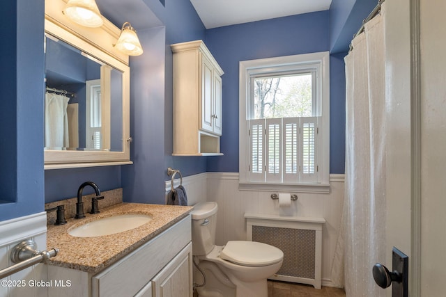 full bath with vanity, radiator, a wainscoted wall, and toilet