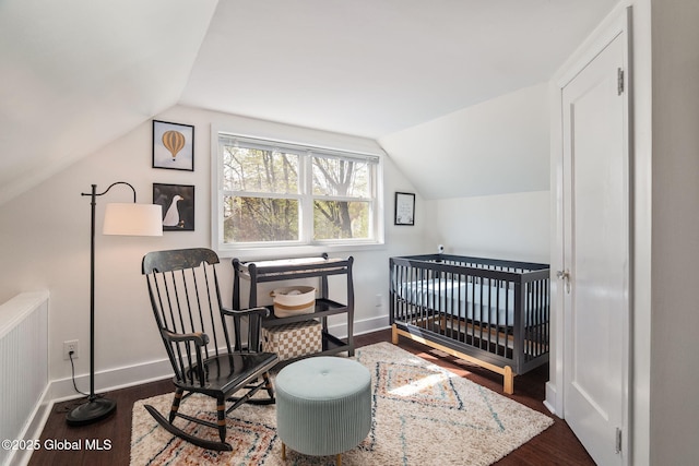 bedroom featuring baseboards, wood finished floors, and lofted ceiling