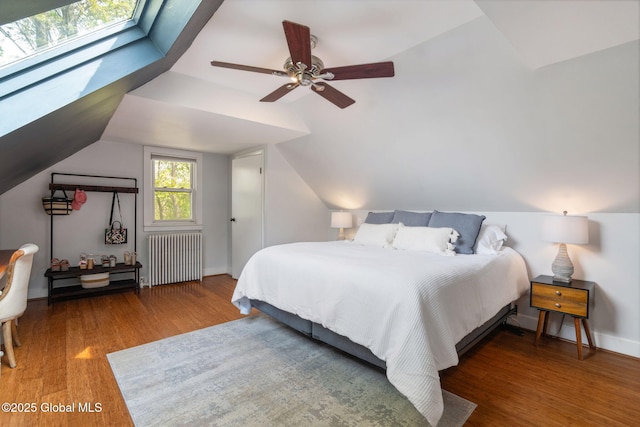 bedroom with ceiling fan, lofted ceiling, wood finished floors, and radiator