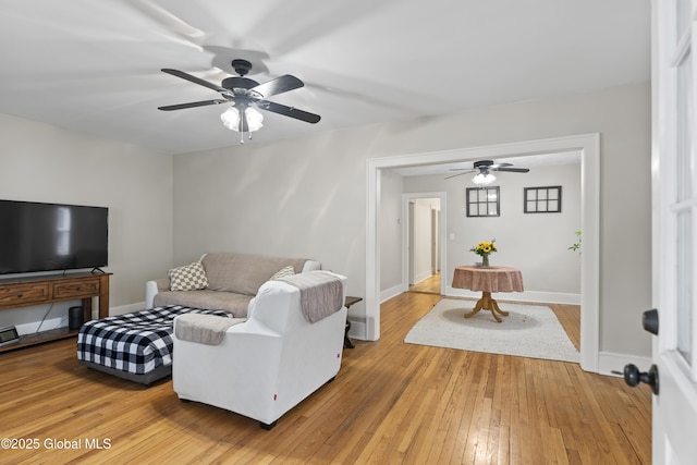 living area with ceiling fan, light wood-style floors, and baseboards