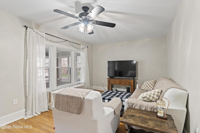 living area featuring baseboards, a ceiling fan, and light wood-type flooring