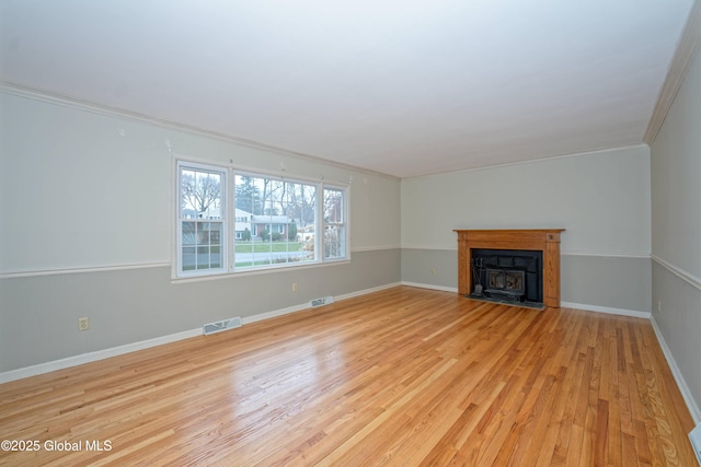 unfurnished living room with light wood-style floors, crown molding, a fireplace with flush hearth, and visible vents