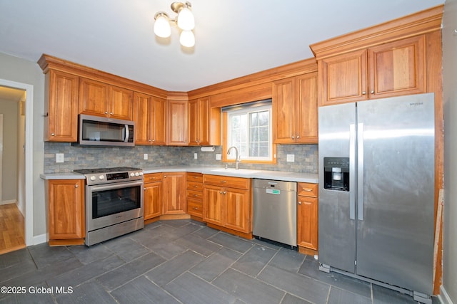 kitchen with a sink, appliances with stainless steel finishes, tasteful backsplash, and light countertops