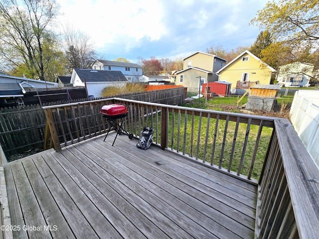 wooden terrace with a fenced backyard, a storage unit, an outbuilding, and a yard