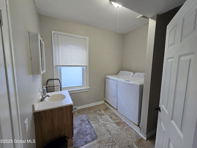 clothes washing area with laundry area, stone finish flooring, a sink, baseboards, and separate washer and dryer