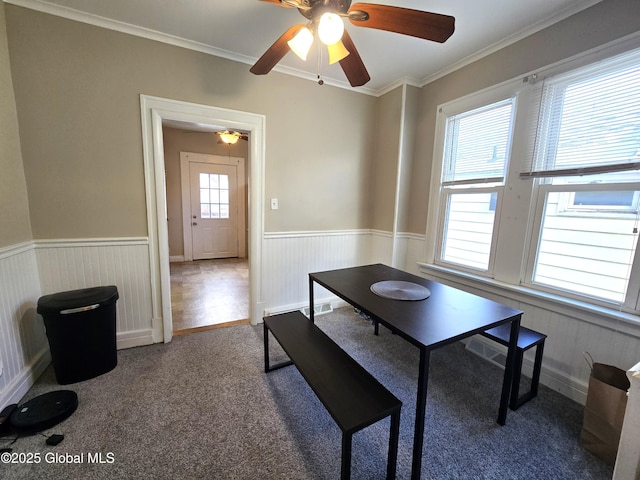 interior space featuring crown molding, a ceiling fan, and a wainscoted wall