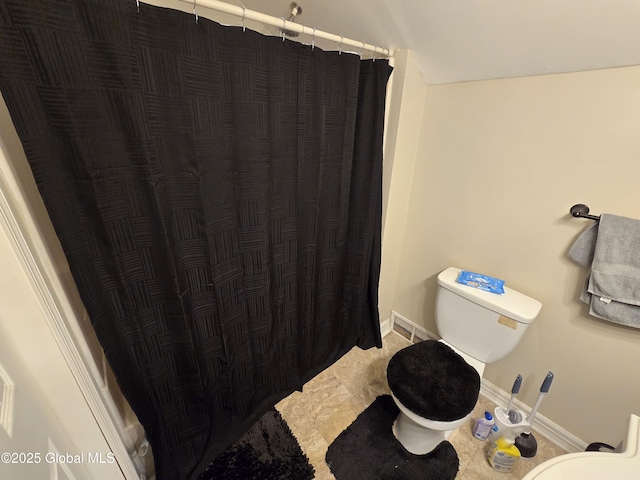 bathroom featuring baseboards, toilet, and curtained shower