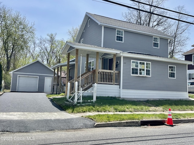 view of front facade with a porch, a garage, an outbuilding, and driveway