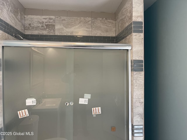 bathroom with a shower with door and toilet