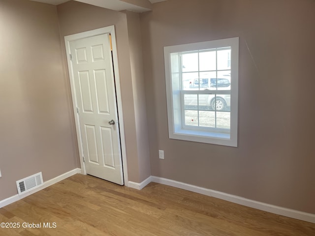 spare room featuring baseboards, light wood-type flooring, and visible vents