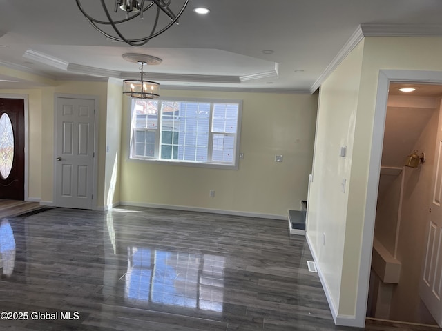 unfurnished dining area with a notable chandelier, baseboards, dark wood-type flooring, a tray ceiling, and ornamental molding