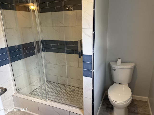 full bathroom featuring baseboards, toilet, and a shower stall
