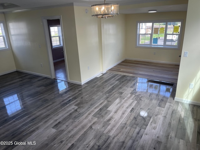 unfurnished dining area featuring baseboards, dark wood finished floors, a chandelier, and visible vents