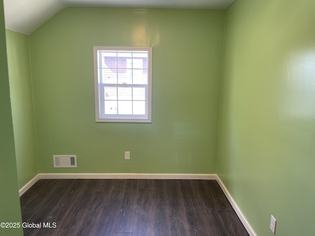 interior space featuring visible vents, dark wood finished floors, baseboards, and vaulted ceiling