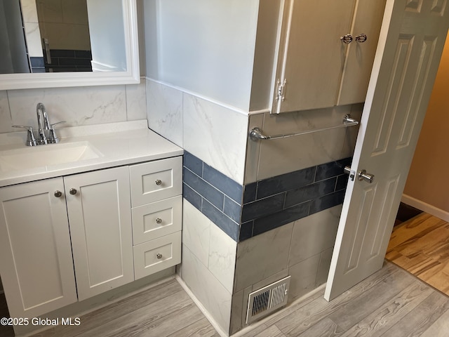 bathroom with visible vents, wood finished floors, tile walls, and vanity