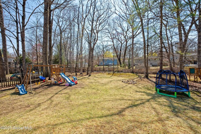 view of yard with a trampoline, a playground, and fence