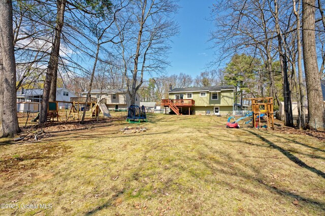 view of yard with stairs, a trampoline, a playground, and a deck