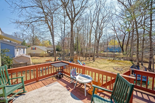 deck with a yard, an outbuilding, a fenced backyard, and a playground