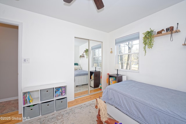 bedroom with a closet, a ceiling fan, baseboards, and wood finished floors