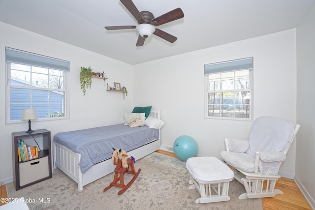 bedroom featuring a ceiling fan, baseboards, and wood finished floors