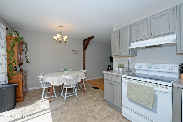 kitchen with white range with electric cooktop, gray cabinetry, light countertops, an inviting chandelier, and under cabinet range hood