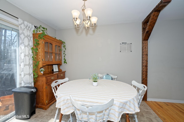 dining space with baseboards, light wood-style flooring, and a notable chandelier