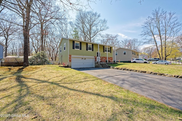 raised ranch featuring an attached garage, aphalt driveway, fence, and a front yard