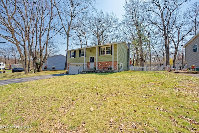 view of front of house featuring a front yard, brick siding, fence, aphalt driveway, and an attached garage