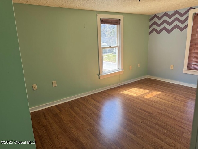 spare room with baseboards and dark wood finished floors