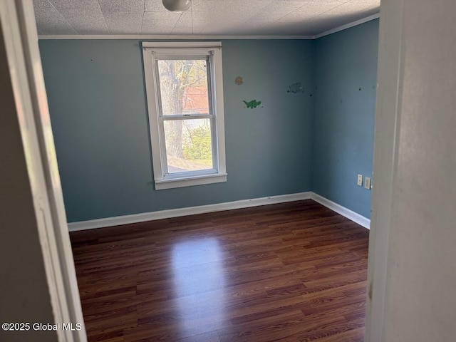 empty room with crown molding, baseboards, and dark wood-style floors