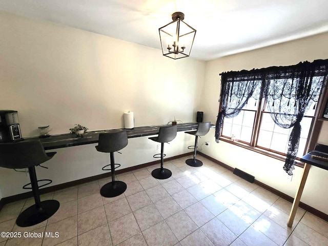 unfurnished dining area featuring baseboards, light tile patterned flooring, and a notable chandelier