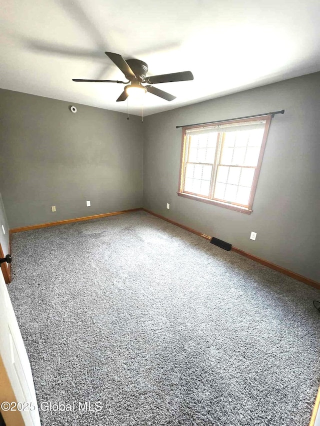 carpeted spare room with baseboards, a ceiling fan, and visible vents