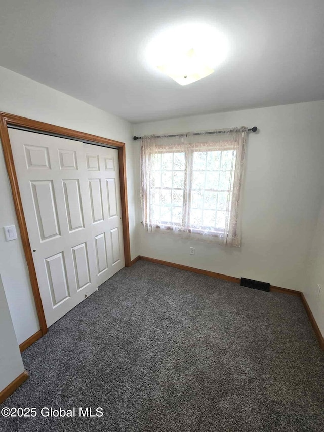 unfurnished bedroom with baseboards, carpet, and a closet