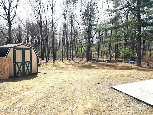 view of yard with an outdoor structure, a wooded view, and a shed