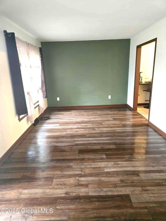 spare room with baseboards and wood finished floors
